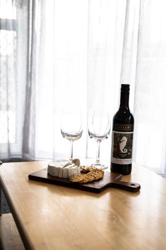 a bottle of wine and two glasses on a table at The Palms Apartments in Merimbula