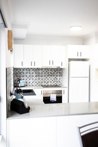 a white kitchen with a sink and a refrigerator at The Palms Apartments in Merimbula