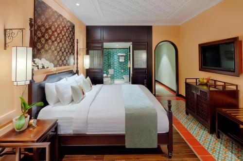 a hotel room with a large bed and a television at Little Riverside Hoi An . A Luxury Hotel & Spa in Hoi An