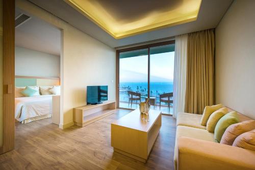 een woonkamer met een bank, een bed en een televisie bij FLC Luxury Hotel Samson in Sầm Sơn