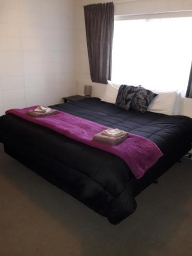 a large bed with two slippers on top of it at Motel Sierra in Whangarei