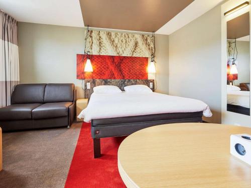 a hotel room with a bed and a couch at ibis Deauville Centre in Deauville