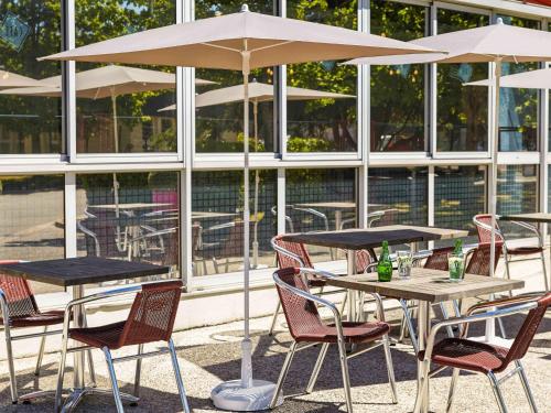 a group of tables and chairs with an umbrella at ibis Chartres Ouest Luce in Chartres