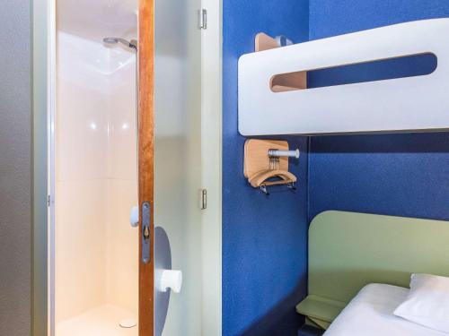 a small bathroom with a bed and a shower at Ibis Budget Sisteron in Sisteron