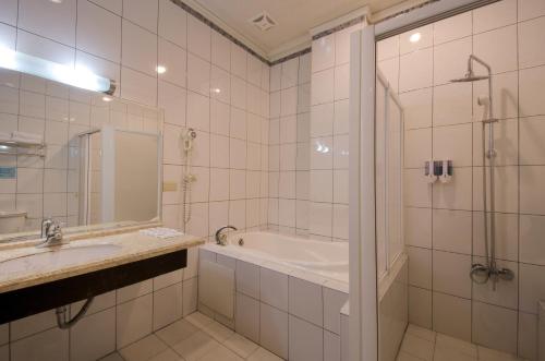 a bathroom with a tub and a sink and a shower at Wogo Hotel in Yilan City