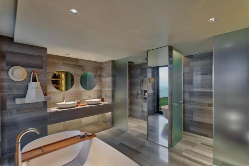 ein Badezimmer mit zwei Waschbecken und einer Badewanne in der Unterkunft Six Senses Zil Pasyon, Seychelles in Felicité