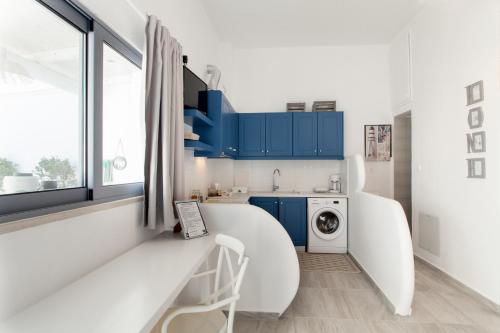 a white kitchen with blue cabinets and a washing machine at Mythos Suites Diskos in Léntas