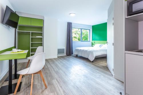 - une chambre avec un lit et un bureau avec une chaise dans l'établissement Atao Residence- Rennes Sud, à Vern-sur-Seiche