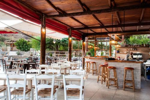 a restaurant with white tables and chairs and a bar at Mythos Suites Diskos in Léntas
