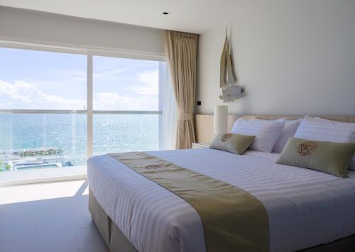 a bedroom with a large bed with a large window at Worita Cove Hotel in Na Jomtien