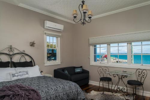 um quarto com uma cama, uma cadeira e janelas em The Ark Stanley Luxury Bed and Breakfast em Stanley