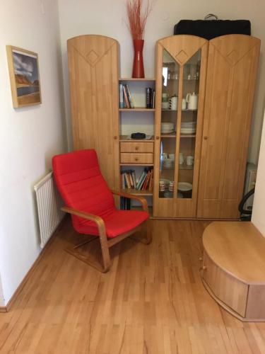a red chair in a room with a book shelf at Ferienwohnung "Die 14" in Steinach am Brenner