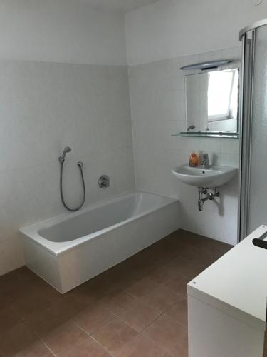 ein weißes Badezimmer mit einer Badewanne und einem Waschbecken in der Unterkunft Ferienwohnung "Die 14" in Steinach am Brenner
