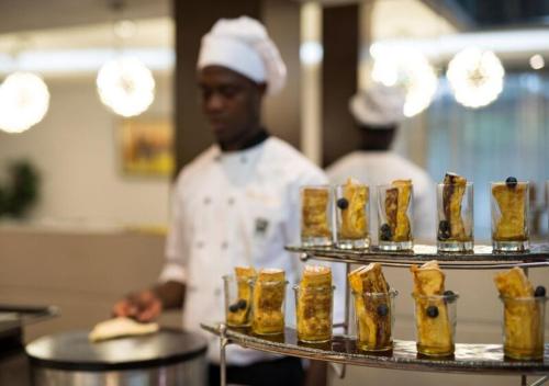 a chef standing in a kitchen preparing food at The Envoy Hotel Abuja in Abuja