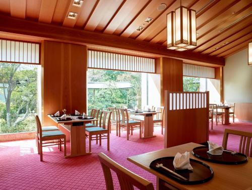 a dining room with tables and chairs and windows at Hotel Okura Kobe in Kobe