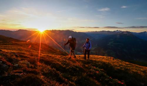 Zwei Personen stehen bei Sonnenuntergang auf einem Berggipfel. in der Unterkunft Hotel Eckartauerhof in Mayrhofen