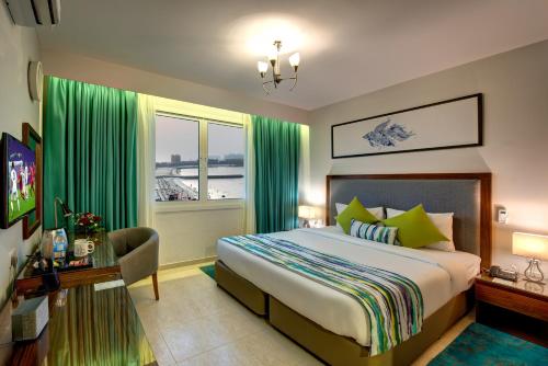 a bedroom with a bed and a window with green curtains at City Stay Beach Hotel Apartments - Marjan Island in Ras al Khaimah