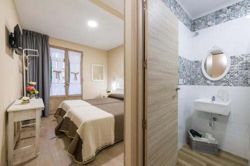 - une petite chambre avec un lit et une salle de bains dans l'établissement Pensión Luis, à Arzúa