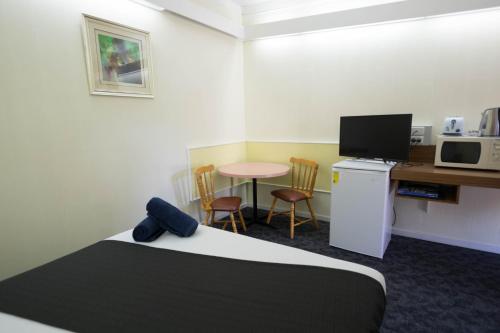 a hotel room with a bed and a desk and a table at Pioneer Station Motor Inn in Swan Hill
