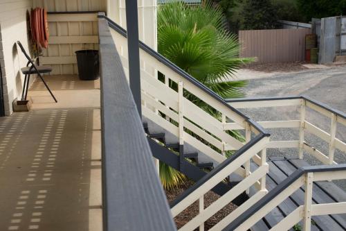 a white railing next to a house with a plant at Pioneer Station Motor Inn in Swan Hill