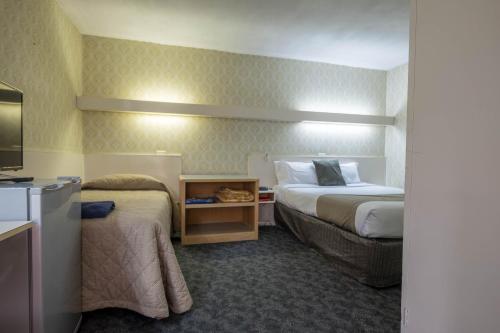a hotel room with two beds and a television at Pioneer Station Motor Inn in Swan Hill