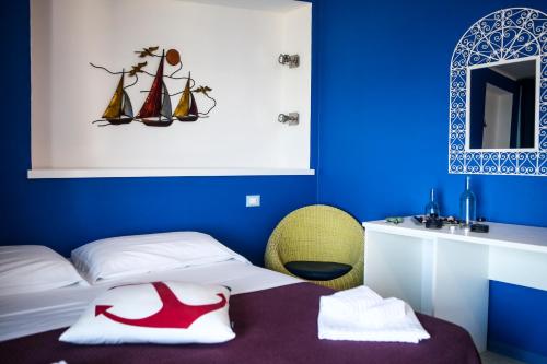 a blue room with a bed and a mirror at Hotel La Favorita in Cala Gonone