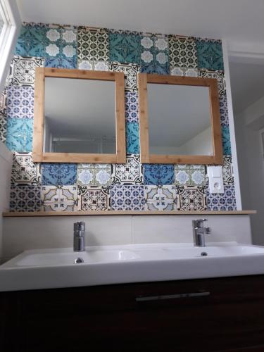La salle de bains est pourvue de 2 miroirs et d'un lavabo. dans l'établissement Maison de bord de mer à Keriec, à Trélévern