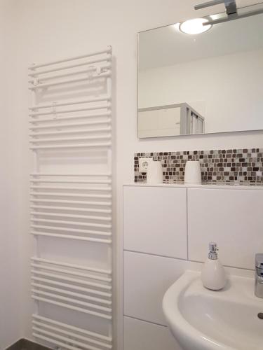 a white bathroom with a sink and a mirror at Greenments, Apartments für Freizeit und Beruf in Geesthacht