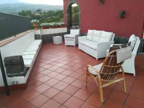 a patio with white chairs and a couch at Villa Pace in Piedimonte Etneo