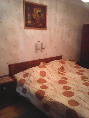 a bedroom with a bed with a painting on the wall at Бабушкин уют в РУСТАВИ in Rustavi