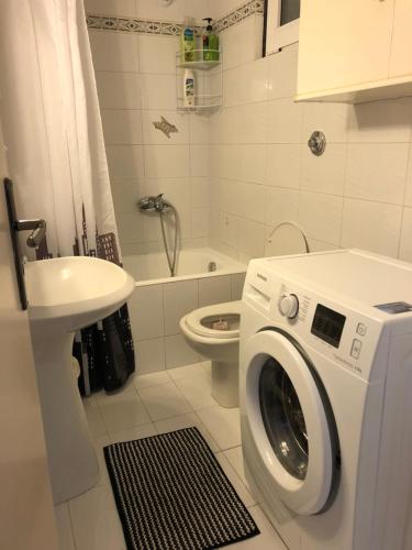 uma casa de banho com uma máquina de lavar roupa e um lavatório em Cozy City Apt em Heraclião