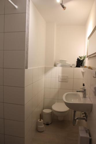 a white bathroom with a toilet and a sink at Die alte Stadtmühle von Kloster Zinna in Jüterbog