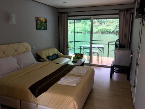 Un dormitorio con una cama y un balcón con una mesa. en River Hill Side Resort, en Ban Tha Thong Mon