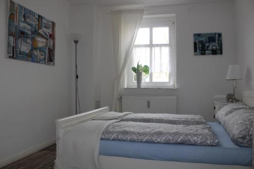 a white bedroom with a bed and a window at Die alte Stadtmühle von Kloster Zinna in Jüterbog