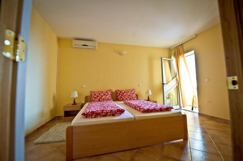 a bedroom with a bed with red pillows on it at Apartmani Ibolja in Promajna