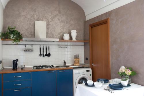 uma cozinha com armários azuis e uma máquina de lavar roupa em La Finestra sul Borgo em Alba