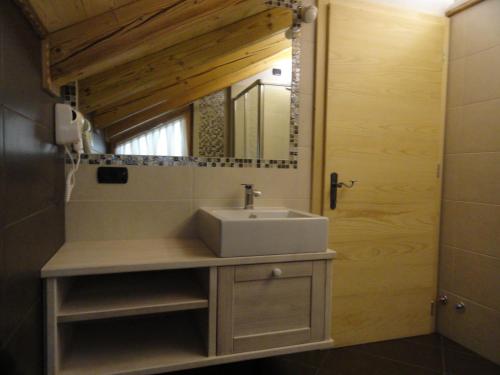 ein Bad mit einem Waschbecken und einem Spiegel in der Unterkunft B&B Mas di Zonadi in Rabbi
