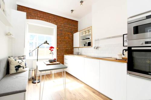 a kitchen with white cabinets and a table at Stylish Flat in 1860's Listed Building in Edinburgh