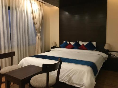 a bedroom with a bed and a table and a window at Kaveri Inn in Kathmandu