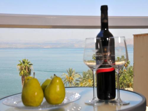 a bottle of wine and pears on a table with a glass at Family Vacation by Lake Kinneret in Tiberias