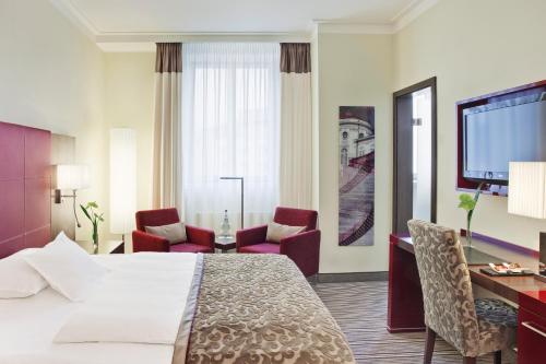 ein Hotelzimmer mit einem Bett, einem Schreibtisch und Stühlen in der Unterkunft Steigenberger Graf Zeppelin in Stuttgart