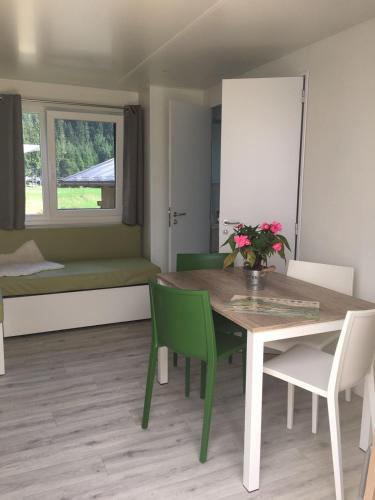 a dining room with a table and green chairs at Eirl DOLOMITES Retreat Sappada in Sappada