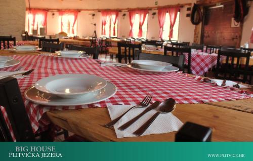 a table with plates and silverware on a red and white table cloth at House Korina B&B in Ličko Petrovo Selo
