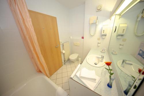 a bathroom with a sink and a toilet and a mirror at Hotel Chassalla in Kassel