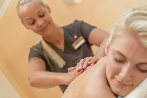 a woman getting a back massage from a therapist at Chalet Silvretta Hotel & Spa in Samnaun