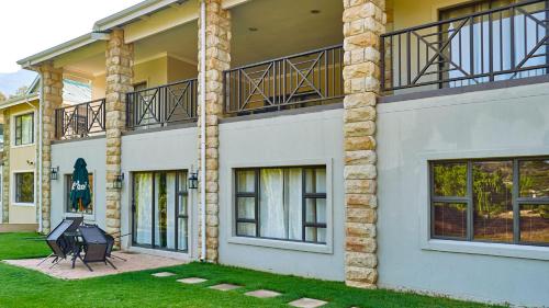 a large white building with a patio and balcony at Pond End Villa in Clarens