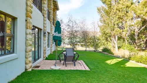 a patio with two chairs and a table and an umbrella at Pond End Villa in Clarens