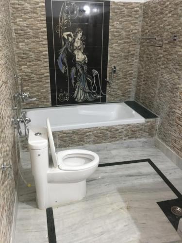 a bathroom with a toilet and a bath tub at CHÉRI HOME Stay in Khajurāho
