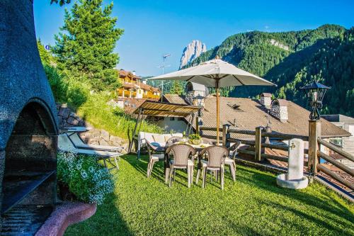 a table and chairs with an umbrella in the grass at Cesa Sara in Ortisei