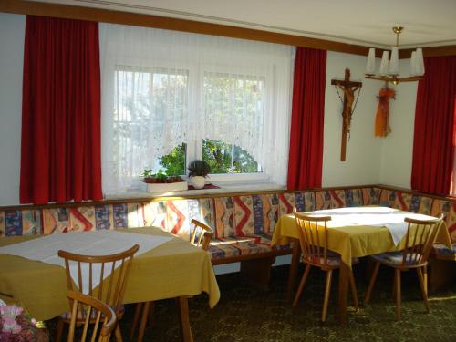 a dining room with two tables and red curtains at Haus Venetblick in Wenns